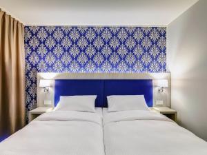 a bedroom with a blue wall and two beds at ibis Styles Rastatt Baden-Baden in Rastatt