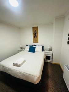 a bedroom with a large white bed with blue pillows at El Refugio in Puerto Natales