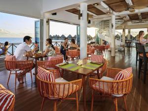 a group of people sitting at tables in a restaurant at Mercure Maldives Kooddoo - Adults-Only Escape in Maamendhoo