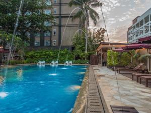 a swimming pool with chairs and a building at Ibis Melaka in Malacca
