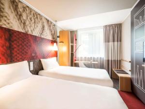 a hotel room with two beds and a large window at Ibis Gdansk Stare Miasto in Gdańsk