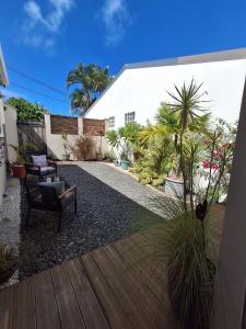 a backyard with a wooden deck and a white building at La Parenthèse 2 Rêves in Saint-Joseph