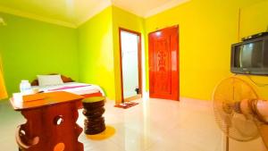a yellow room with a bed and a tv at Sam So Guesthouse in Siem Reap