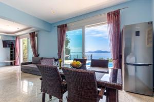 a living room with a table and a refrigerator at Daniella with Seaview Pool in Nisaki