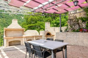 an outdoor patio with a table and a fireplace at Daniella with Seaview Pool in Nisaki
