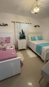 a bedroom with two beds and a chandelier at El rincón de Sánchez in Moca