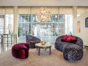 ein Wohnzimmer mit Sofas, einem Tisch und einem Kronleuchter in der Unterkunft Mercure Hotel Schweinfurt Maininsel in Schweinfurt