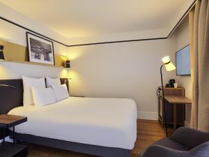a hotel room with a white bed and a chair at Mercure Paris Saint-Ouen in Saint-Ouen +75 photos