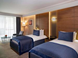 a hotel room with two beds and a chair at Mövenpick Hotel & Thermal Spa Bursa in Bursa +171 photos