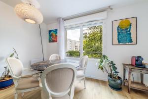 a dining room with a table and chairs and a window at Escapade du Stade BY UTA HOUSE in Saint-Denis