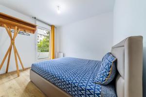 a bedroom with a bed with a blue comforter at Escapade du Stade BY UTA HOUSE in Saint-Denis