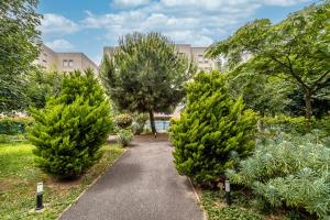 a walkway through a garden with two trees at Escapade du Stade BY UTA HOUSE in Saint-Denis