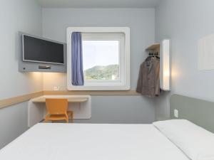 a room with a bed and a desk and a window at ibis budget Blumenau in Blumenau