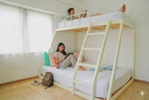 two people sitting on top of a bunk bed at Bangkok Group Bunk Hotel Khaosan in Bangkok