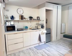 a kitchen with white cabinets and a microwave and a refrigerator at Ernie MyeongDon'g Sation 1Min, Anytime Check In in Seoul