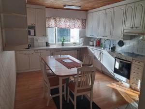 a kitchen with white cabinets and a table and chairs at Jänispolku in Rauma
