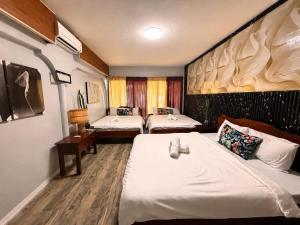 a hotel room with two beds and a desk at Aloha Ocean View Resort in Pandan +5 photos
