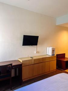 a hotel room with a bed and a tv on the wall at Vu Exclusive Boarding House in Kerobokan