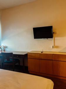 a room with a tv on a wall with a desk at Vu Exclusive Boarding House in Kerobokan