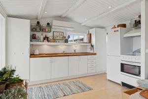 a kitchen with white cabinets and white appliances at Classic Danish Holiday Home in Karrebæksminde