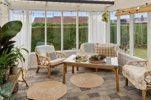 a screened in porch with chairs and a coffee table at Classic Danish Holiday Home in Karrebæksminde
