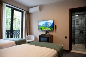 a hotel room with two beds and a tv on the wall at Borjomind Hotel Borjomi in Borjomi