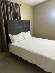 a bedroom with a bed with white sheets and pillows at Manor Villas in Kingston