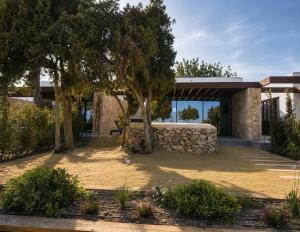 a house with a stone wall and trees in front of it at Can Skye in Sant Carles de Peralta