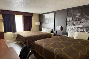 a hotel room with two beds and a table at Super 8 by Wyndham Fountain in Fountain +8 photos