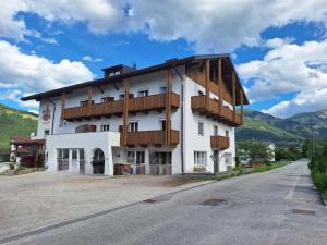 a large white building with wooden balconies on a street at Hotel Pörnbacher in Valdaora