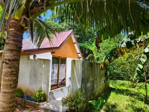 a small house with a palm tree next to a fence at KhaoSok Farmstay in Khao Sok National Park