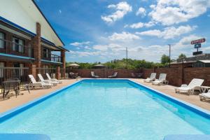 a large swimming pool with chairs and a building at Days Inn by Wyndham Clanton AL in Clanton