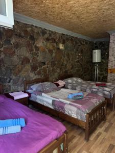 ein Zimmer mit drei Betten und einer Steinwand in der Unterkunft SADA Guesthouse in Wardsia