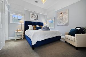 a bedroom with a blue bed and a chair at Roseberne Cottage, Luxury in the CBD! in Bathurst