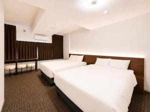 two beds in a hotel room with white sheets at Residence Hotel Liberte in Sapporo