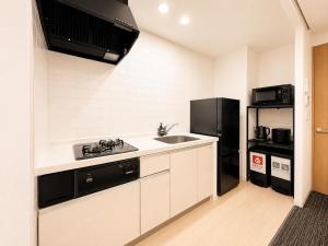 a kitchen with a sink and a black refrigerator at Residence Hotel Liberte in Sapporo