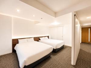 two beds in a hotel room with white walls at Residence Hotel Liberte in Sapporo