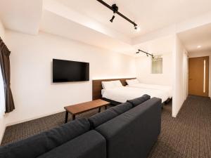 a living room with a couch and a tv at Residence Hotel Liberte in Sapporo