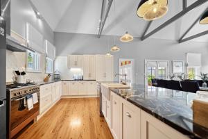 a large kitchen with white cabinets and black counter tops at Roseberne Cottage, Luxury in the CBD! in Bathurst