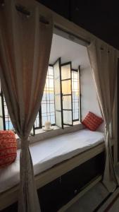 a bed with curtains in a room with windows at Hardik villa in Udaipur