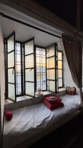 a bed with four windows in a room at Hardik villa in Udaipur