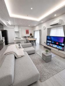 a living room with a couch and a flat screen tv at Room 701 Large 3LDK 98sqm Near Namba Big Balcony Ideal for Groups and Long Stay in Osaka