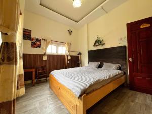 a bedroom with a large bed with a wooden headboard at TeeDalat House in Khu Chi Lăng +4 photos