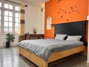 a bedroom with a large bed with an orange wall at TeeDalat House in Khu Chi Lăng