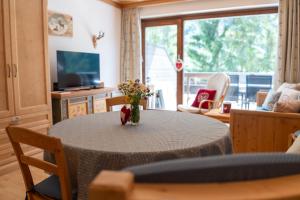 a living room with a table with a vase of flowers on it at Herzerl Apartment - Heiligenblut in Heiligenblut