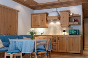 a kitchen with wooden cabinets and a table with blue chairs at Herzerl Apartment - Heiligenblut in Heiligenblut