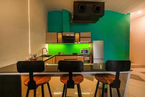a kitchen with green walls and a counter with stools at Stay XO - A Luxurious 3BHK Villa in Panchkula in Panchkula