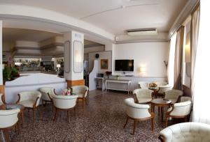 una sala de espera con mesas, sillas y TV en Hotel Regina, en Alassio
