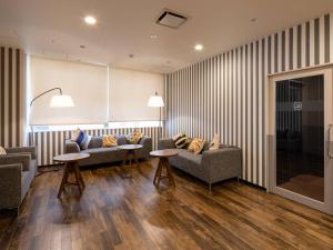 a living room with two couches and two tables at Comfort Hotel ERA Kobe Sannomiya in Kobe