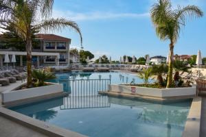 a swimming pool with palm trees in a resort at Dennys Inn Hotel in Kalamaki